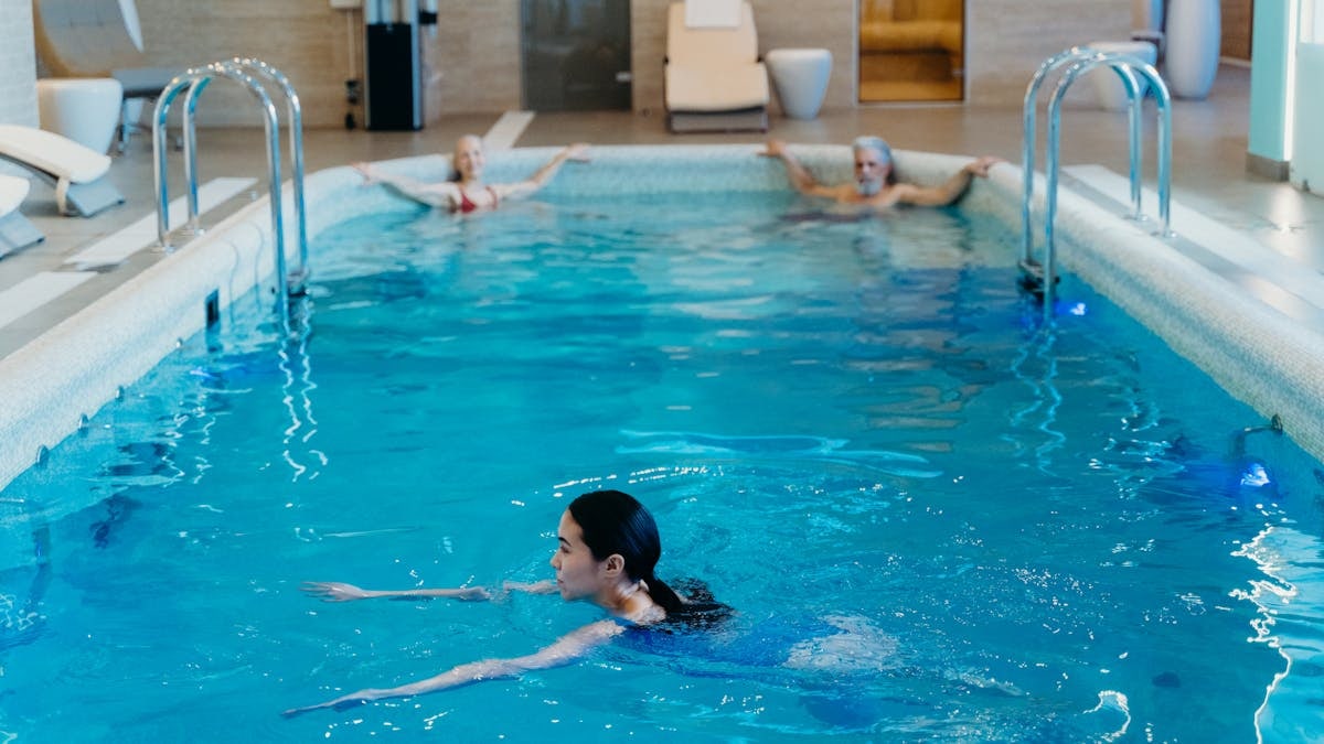 Adults relaxing and swimming in a serene indoor pool setting, perfect for leisure and recreation.